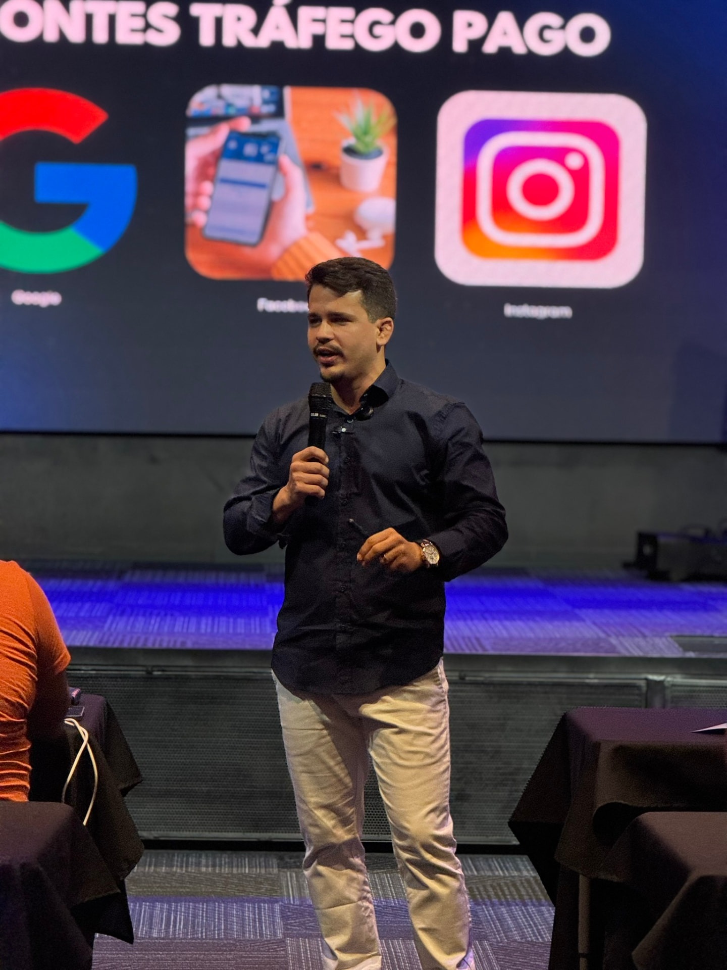 Antonio Filho apresentando uma palestra sobre tráfego pago, com os logos de Google, Facebook e Instagram ao fundo